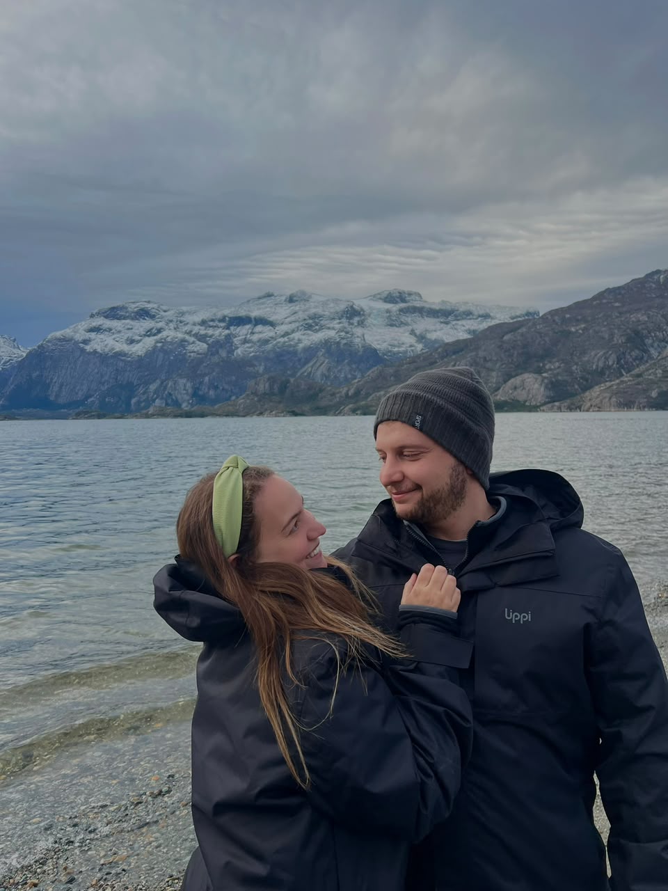La pareja mirándose junto a un lago cordillerano